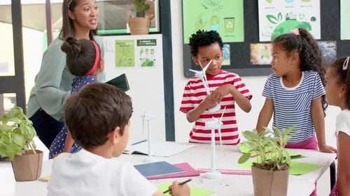 In school, teacher and students discussing science project with wind turbines