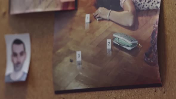 A detective's hands organize crime scene photos on an evidence board ...