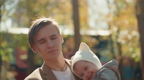 Dad Hugs Baby Father and Child in Park Father Gently Holds Infant Under Autumn Sky Silent Father