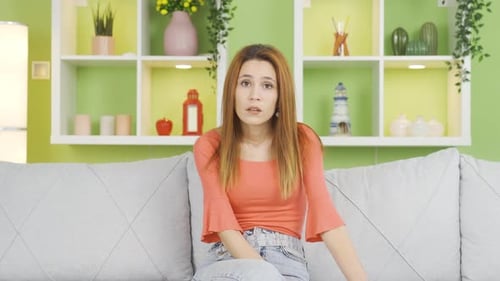 Startled Young Woman on Couch Reacting to News