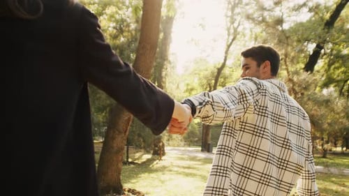 Young Guy Taking His Girlfriend By the Hand on a Walk in the Park
