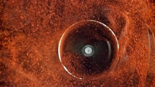 Reddish-Brown Powder Swirling in Clear Container, Close Up