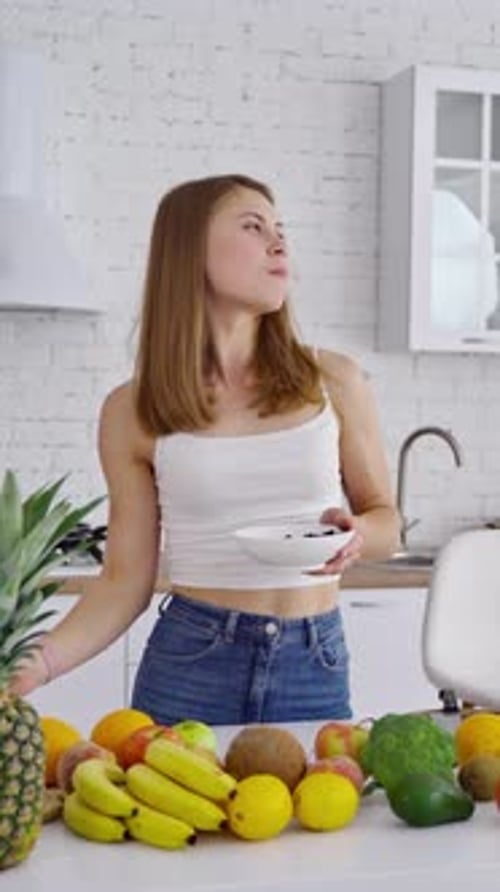 Young Woman Enjoys Fruit in Bright Kitchen