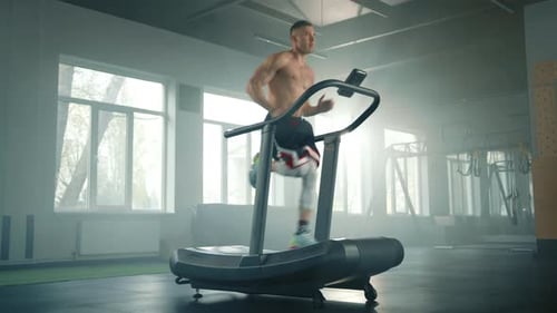Full Shot of Athletic Young Man Running Fast on Treadmill in Spacious Empty Gym