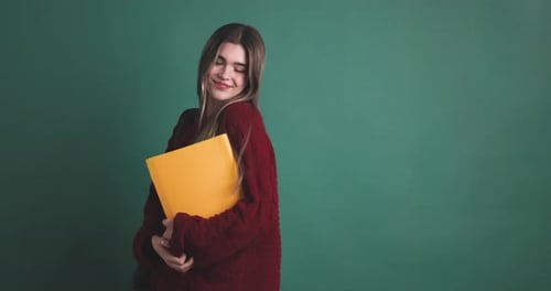 Smiling Student Holding Folders in Front of School