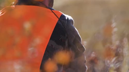 Hunter waits in the woods by his rifle. Close Up pans from face to rifle. Slow Motion. 4K