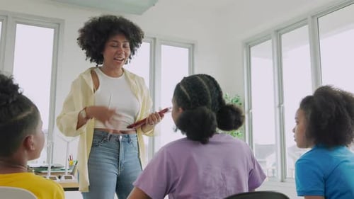 African American woman teacher Explains Lesson to group of elementary school students in classroom
