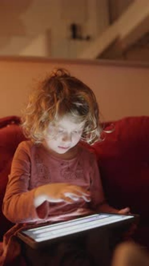 Small Girl Plays or Watches a Tablet Computer in Vertical