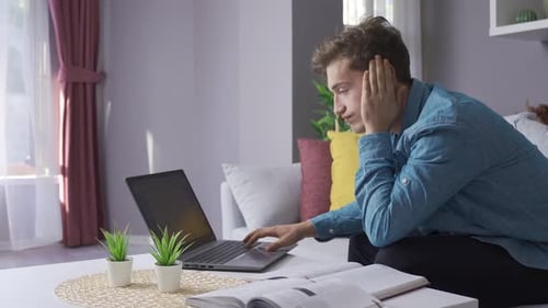 Gestresster männlicher Student schaut auf Laptop.
