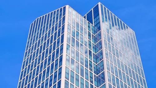 Timelapse of moving clouds on a business office building over blue sky