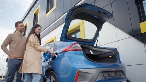 Happy young couple smiling outdoor at EV charging station