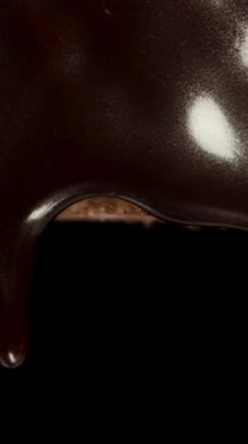 Vertical video. Dark chocolate fully covers the waffle. Black background. Macro slider shot.