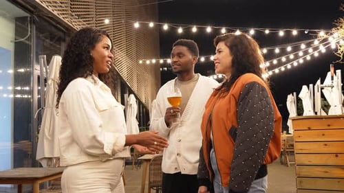 Friends Talking and Smiling on Restaurant Patio at Night