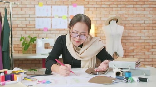 Asian female fashion designer works by idea drawing sketches for a dress design.