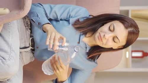 Vertical video of The sick young woman drinks a lot of water.