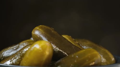 Pickled Cucumbers Spinning on a Black Background Salt Cucumbers in a Bowl Rotating on Turntable