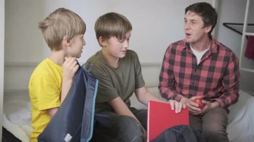 Pai ajuda seus dois filhos a se prepararem para a escola em casa