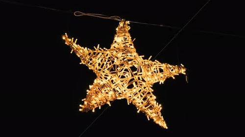 A star-shaped garland glows on the streets of the evening city.