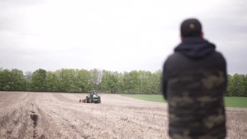 farmer watching his tractor planting sunflower at the field