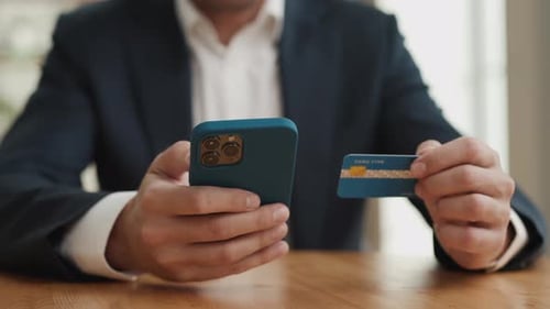 Man hand holds credit card and shops online with mobile phone close up
