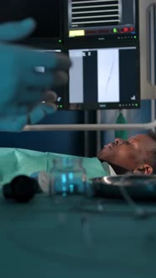 Vertical of Darkskinned Patient on the Operating Table Against the Background of Surgeons' Hands