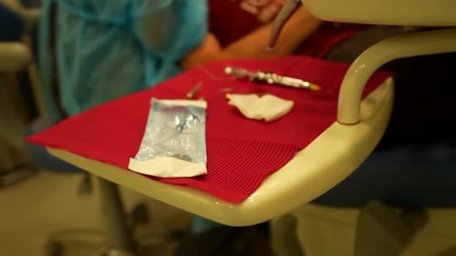 Portable table with sterilized dental tools while a dentist works in background in a dental clinic