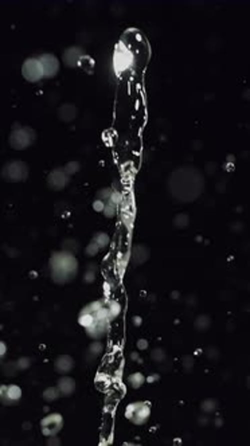 Water Stream and Droplets on Black Background