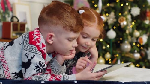 Children Using Tablet Device Near Christmas Tree