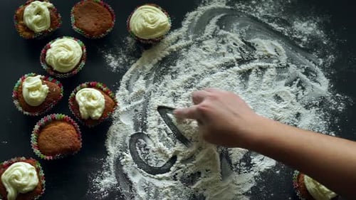 Drawing Cake in Flour with Cupcakes Around