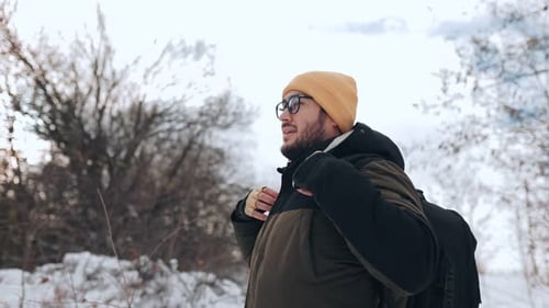 Man Hikes Through Snowy Woods in Winter