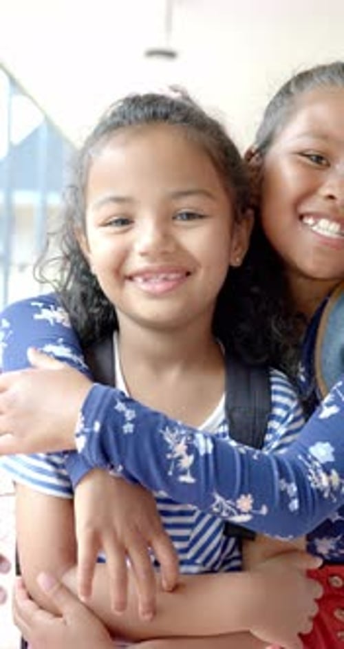 Vídeo vertical: na escola, três jovens amigas birraciais estão se abraçando