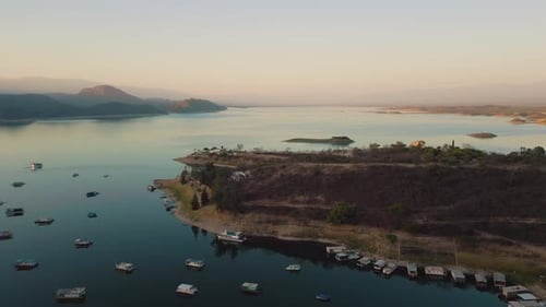 Aerial drone flying over a lake, water dam, with mountains at sunrise. Beautifull dreamy landscape