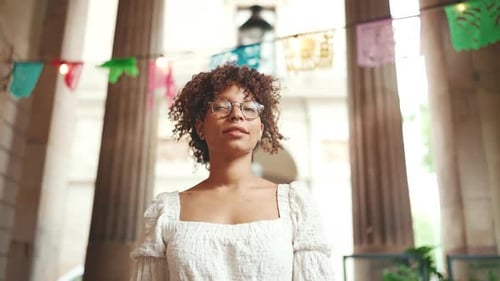 Stylish Woman with Glasses Posing in Decorated Courtyard