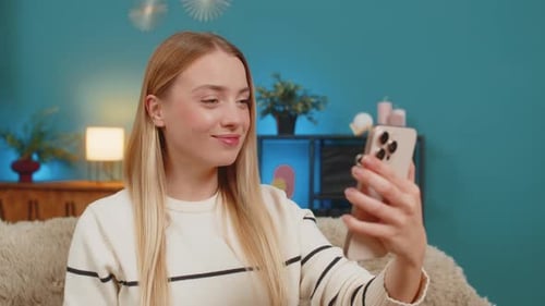 Smiling Young Woman Video Calling on Phone Indoors