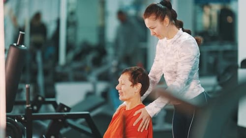Personal Fitness Trainer Assisting Senior Woman in Gym