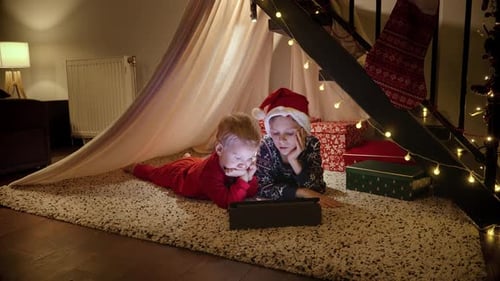 Two Children Watch Tablet Under Christmas Tent