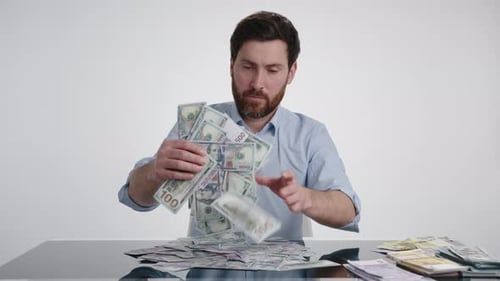 Ein Mann in einem blauen Hemd kombiniert Geld zu einem großen Haufen auf dem schwarzen Tisch
