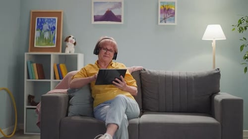 Woman Using Tablet on Couch With Headphones
