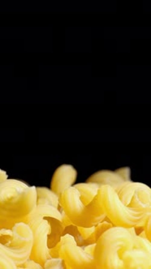 Raw macaroni pasta falls gracefully in stunning slow motion.