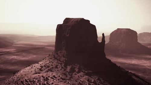 Majestic Rock Formation at Sunrise Over Desert Landscape