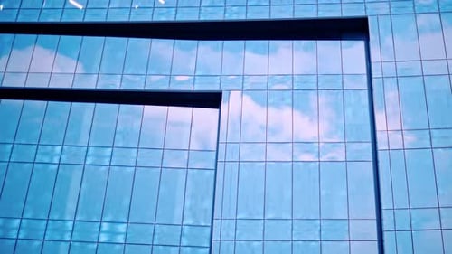 The sky being reflected on a building with glass walls