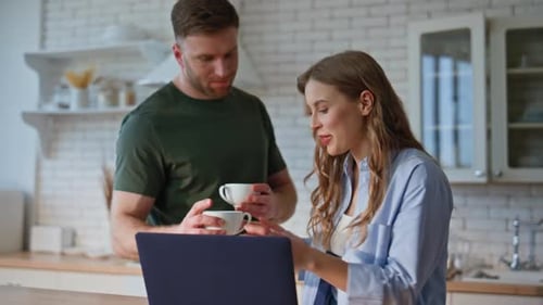 Young Adults Looking at Laptop in Kitchen