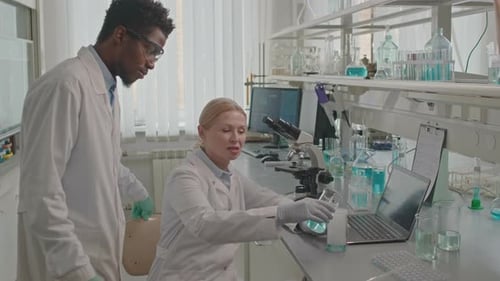 Scientists Working with Blue Liquid in Laboratory