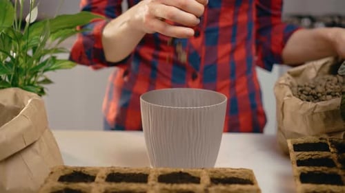 Woman Adds Soil to a Potted Plant