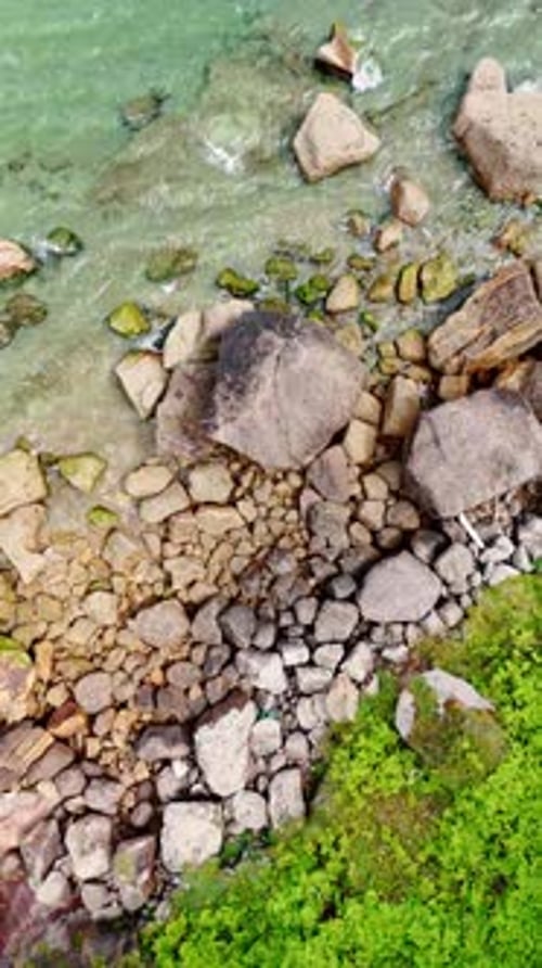 Grey boulders of diverse size at the coastline of the sea.