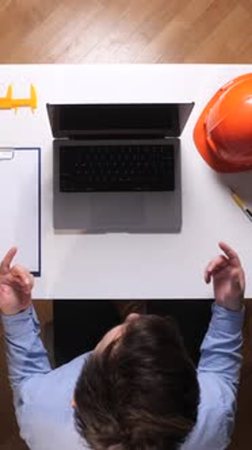 Vertical Video Engineer Planning a New Architectural Project Sitting at a Desk with an Open Laptop