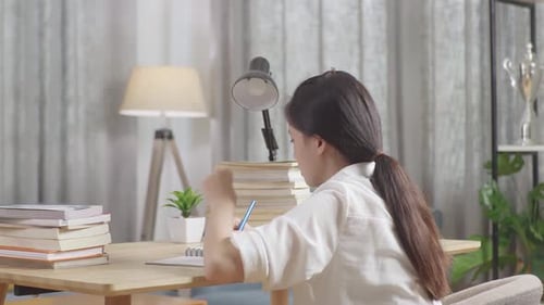 Back View Of Tired Asian Teenager Yawning While Studying At Home, Doing Home Work