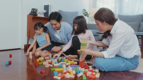 Asiatische Familie mit spielenden Kindern und Bauturm aus buntem Holzspielzeug