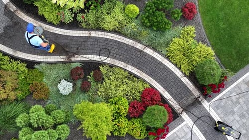 Man Pressure Washing Garden Path Using Modern Pressure Washer