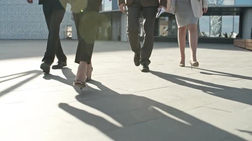 Legs of four business people walking on the pavement
